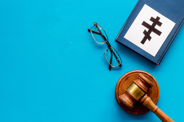 Ortodox cross - Christianity symbol - near gavel on blue background top-down. Religious conflict concept. Copy space