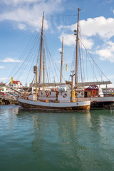Obraz premium Whale watching ship or fishing vessel in Husavik harbour in Iceland during sunny day.