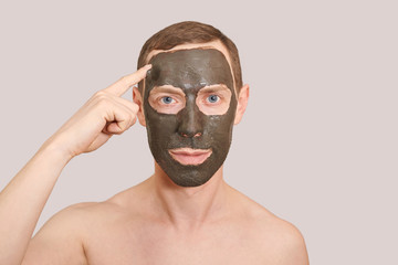 Black Clay Mask on Guy Face. Cosmetology man portrait with mud healthy scrub. Coal nature eco masque. Dermatology mud. Home skin care routine. Skincare male treatment. Applying pure ecology product