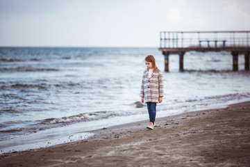 Fototapeta na wymiar Portrait of little fashionable girl walking near sea