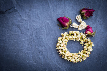 Dry roses steering wheel on nature black stone slate , top view with copy space