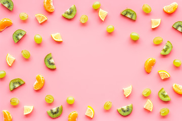 Slices fruites frame. Fruit salad concept with citruses, aplle and kiwi on pink background top-down copy space