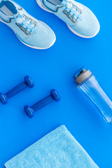 Sport flat-lay with dumbbells, towel, sneakers on blue background top-down
