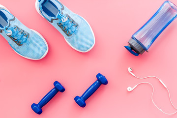 Sport flat-lay with sneakers and water on pink table top view