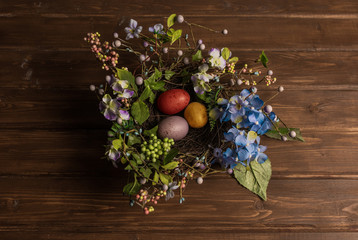 Nest with easter eggs on wooden background.  Top view, flat lay.