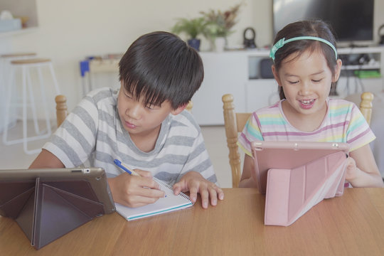 mixed Asian girl using digital tablet at home, listening to podcast, gaming, online education, elearning, homeschooling, social distancing, isolation, new normal concept