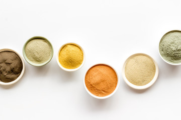 Yellow, red, white, blue and black cosmetic clay on white table top view