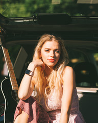 Fototapeta na wymiar Girl with guitar on hatchback car