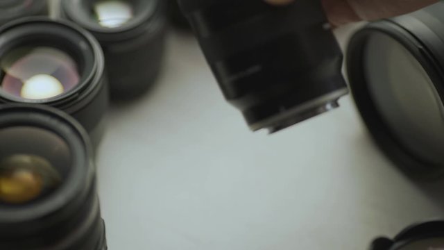 A hand picking down the lens of the camera between another lens. tools of trade close up video