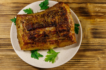 Baked pork belly in a plate on wooden table. Top view