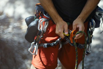 Climber's hands and various climbing equipment during preparation for climb, close-up.
