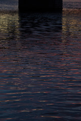 Dreamy bright colorful surface of water with little waves with black, yellow and blue stripe on sunset, abstract background, texture.