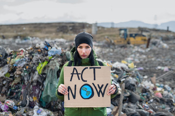Woman activist with placard poster on landfill, environmental pollution concept.