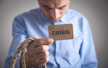 Man holding Crisis text on cardboard card.