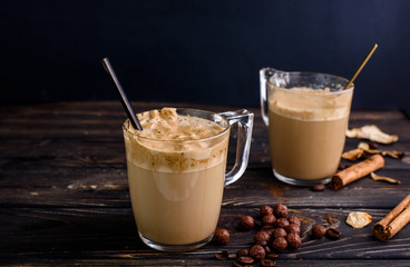 Delicious and fragrant dalgona coffee in glass cups, cinnamon sticks, dried mushrooms, a spoon of instant coffee, sugar. Cooling coffee drink with milk
