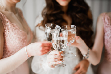 Photo bride with her friends drinking champagne from glasses