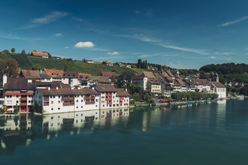 Fototapeta na wymiar Reflections of medieval town houses and buildings along the river Rhine in the Swiss village of Eglisau in Switzerland