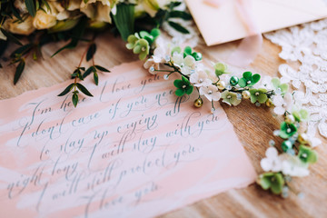 Wedding composition decorated with green white pearl floral jewelry and invitation letter on the wooden table. Jewelry closeup details from morning of the bride.