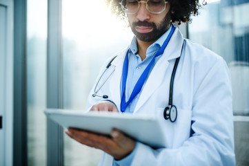 Portrait of worried doctor with tablet standing in hospital. Copy space.