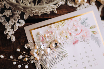 Wedding composition decorated with  pearl jewelry and invitation letter on the wooden table with lace. Jewelry closeup details from morning of the bride.