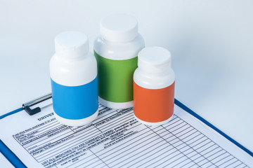 Three bottles of pills on the table with a patient file