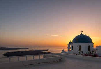Obraz premium A beautiful sunset over the Caldera in Santorini overlooking two iconic blue dome churches in Imerovigli
