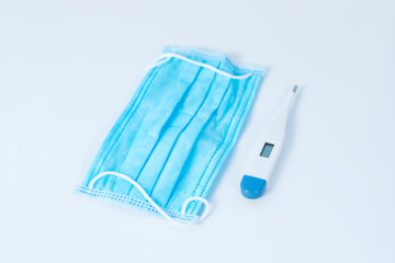 Protective mask and digital thermometer laying on the table