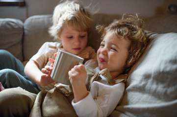 Two small sick children brother and sister at home lying in bed.