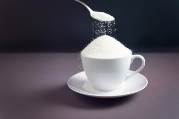 Sugar on a dark background with a spoon. Concept of harm health