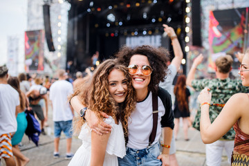 Young girl friends at summer festival, posing for photograph.