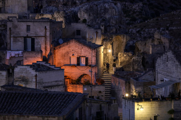  Evening view of the city of Matera, Italy, with the colorful lights highlighting patios of sidewalk cafes in the Sassi di Matera a historic district in the city of Matera. Basilicata. Italy