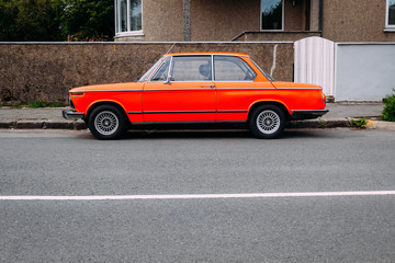 old retro orange car parked near the road in summer on a sunny day