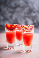 Strong red cocktail in shots on the rustic background. Selective focus. Shallow depth of field.