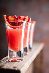 Strong red cocktail in shots on the rustic background. Selective focus. Shallow depth of field.