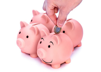  Hand putting coins to smiling piggi bank. Four pink piggy banks isolated against white background  
