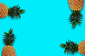 Fototapeta premium Flat lay pineapples with copy space on bright blue background. Seasonal fruit with blank space for your message.