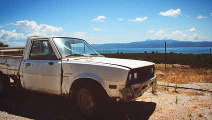 Fototapeta premium Old farm car on dusty road of Lesvos island close by Aegean seaside