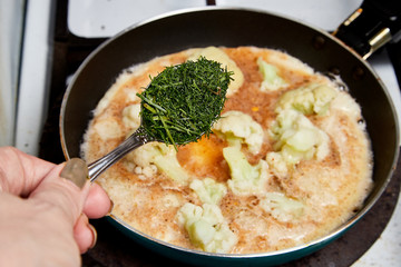 Cooking. Frying Broccoli in a pan with a liquid egg