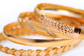 various gold bracelets on a white background