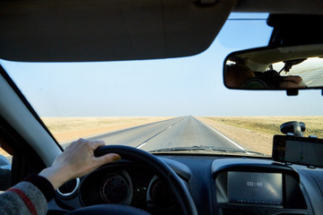 View from car window on the road and landscape with steppe, prairie, wilderness, plain and blue sky. Landscape through windscreen in Kalmykia in Russia