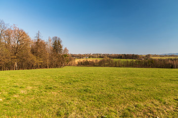 Fototapeta premium rural landscape with mix of meadows, forest, small village and hills on the the background