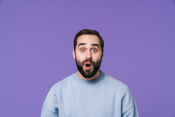 Surprised handsome young man over purple background.