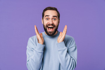 Surprised handsome young man over purple background.