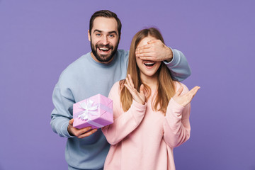 Man covering eyes of his girlfriend holding gift box.