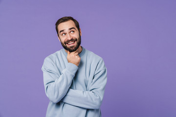 Dreaming positive young man isolated over purple wall