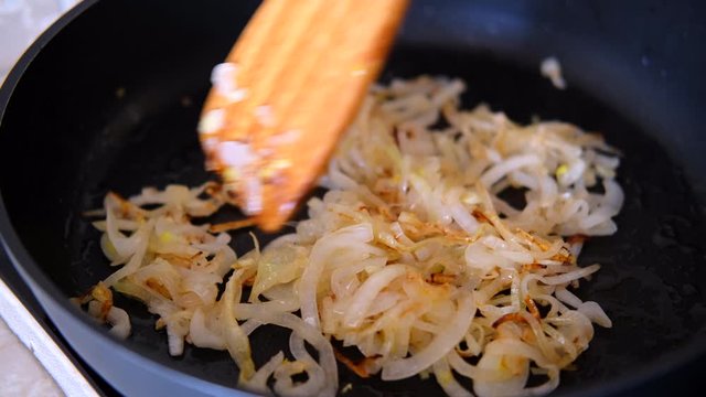 chicken liver with onion fried in the pan with a wooden kitchen spatula