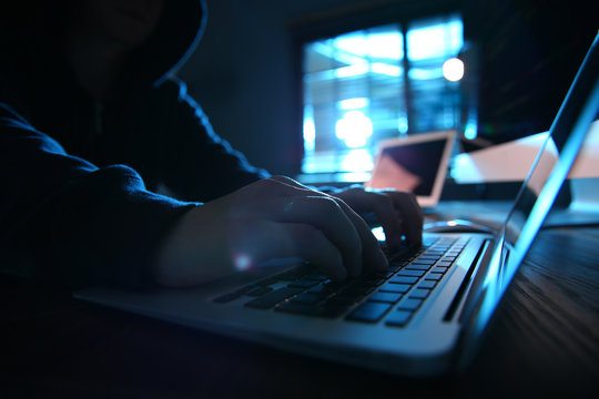 Hacker With Laptop In Dark Room, Closeup. Cyber Crime