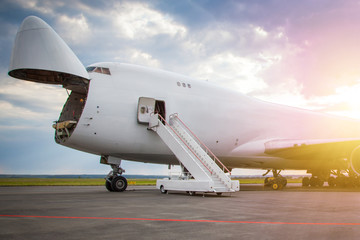 Unloading widebody cargo airplane at the airport apron in the morning sun. Freight aircraft bow...