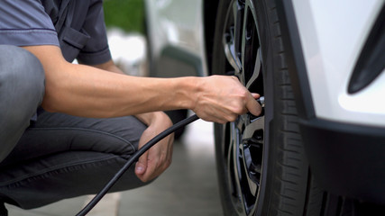 man filling air in the tires of car (inflating tire)