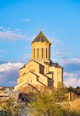 Orthdodox holy trinity church in Tbilisi with many hosues around and blooming spring trees. Religion and culture of Kartvelians. Sakartvelo.